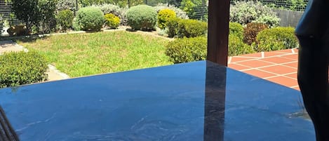A clear view of the ocean from a glass table with a book and a bowl of food.