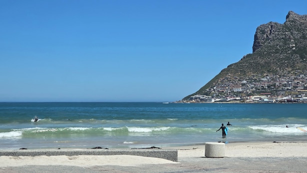 A beach with a rocky hill in the background.