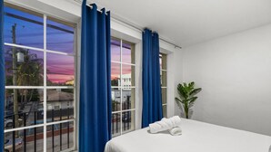 A hotel room with a bed, a window with blue curtains, and a view of the street outside. - Large 2BR Luxury Flat - Near Brickell City Center (Miami)