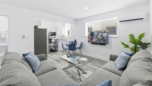 A modern living room with grey sofas, a glass coffee table, and a TV wall art. - Large 2BR Luxury Flat - Near Brickell City Center (Miami)