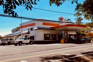 Una estación de servicio con un edificio blanco, un toldo rojo y blanco y una bomba de gasolina.