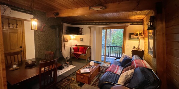 A cozy cabin interior with a dining area, a sofa, and a television. - The Windsong Lodge #3 (Bessemer)