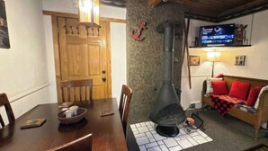 A cozy living room with a fireplace, a television, and a dining area with a table and chairs. - The Windsong Lodge #3 (Bessemer)