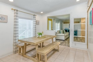 A dining area with a wooden table and benches, a window with blinds, and a view into the living room. - Waterfront! Private Dock, Kayaks, Screened Patio, Less Than 1 mile to Beach, $300 in Free Tickets! (St. Augustine)