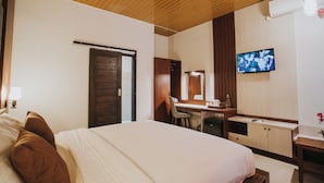 Habitación de hotel con cama, escritorio, silla y televisión.