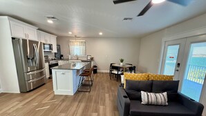 A modern kitchen with stainless steel appliances, a dining area with a table and chairs, and a living room with a sofa and a ceiling fan. - Lakefront oasis offering breathtaking views & relaxation. Perfect for unwinding! (Avon Park)