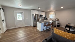 A modern kitchen with a central island, stainless steel appliances, and a dining area with a round table and bar stools. - Lakefront oasis offering breathtaking views & relaxation. Perfect for unwinding! (Avon Park)