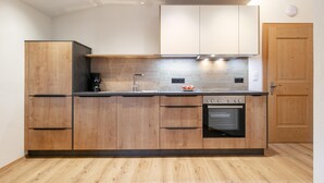 A modern kitchen with wooden cabinets, a built-in oven, and a coffee maker.