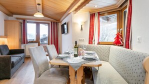 A cozy dining area with a wooden table set for two, surrounded by cushioned seating.