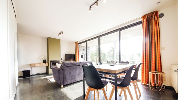 A modern living space with a dining area, a sofa, a TV, and a fireplace. - Beautiful apartment overlooking the golf course (Barvaux)