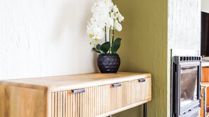 A wooden console table with a black vase containing white flowers. - Beautiful apartment overlooking the golf course (Barvaux)