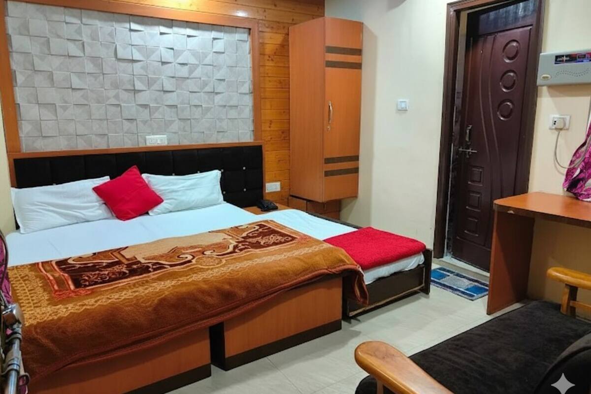 A bedroom with two beds, a wardrobe, a desk, and a door.