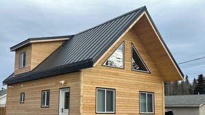 A two-story wooden house with a sloped roof, a front door, and two windows.