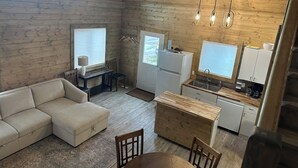 A cozy cabin interior with a living area, kitchenette, and a dining space.