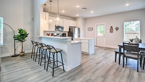 Une cuisine moderne avec des meubles blancs, un îlot central et des tabourets de bar.
