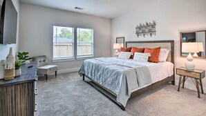 Une chambre à coucher comprenant un lit, des tables de chevet, une commode, une chaise et une fenêtre.