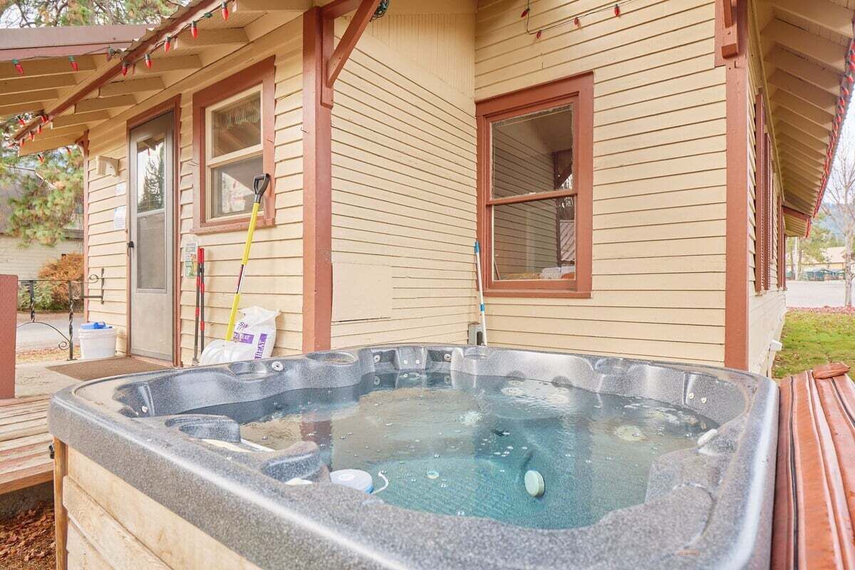 A hot tub outside a house with wooden siding and a covered porch.