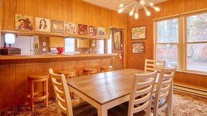 Ein Zimmer mit Holzwänden, einer Bar, einem Esstisch mit Stühlen und Kunstwerken an den Wänden.