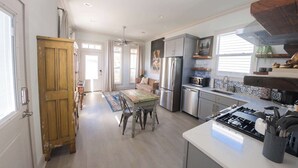 A spacious kitchen with a central island, stainless steel appliances, and a dining area with a wooden table and chairs. - Sunflower Cottage | Cozy Autumn Escape (Pensacola)