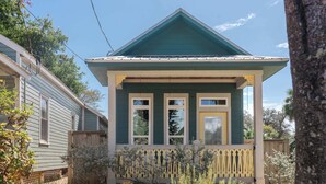 A two-story house with a green roof and a porch with a picket fence. - Sunflower Cottage | Cozy Autumn Escape (Pensacola)