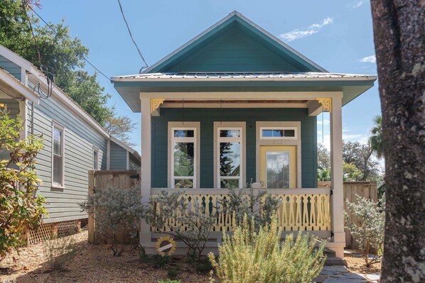 A two-story house with a green roof and a porch with a picket fence. - Sunflower Cottage Downtown (Pensacola)