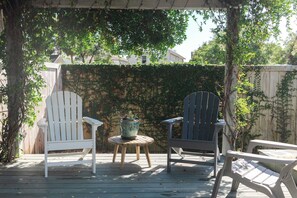 A wooden deck with two Adirondack chairs and a small table. - Sunflower Cottage Downtown (Pensacola)