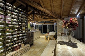 A wine cellar with shelves of wine bottles, a wooden table, and a vase with flowers.