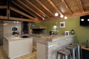 Une cuisine équipée d’un four à briques, d’une cuisinière encastrée et d’un coin bar avec des tabourets.