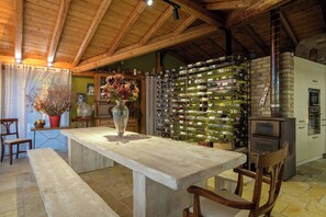 A rustic kitchen with a wooden table, a wine rack, and a stone oven.