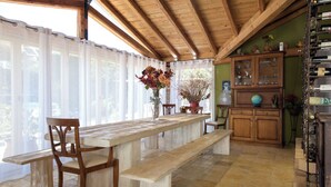 A wooden dining area with a bench and chairs, a table, and a cabinet with glass doors. - Villa Irida - Holiday home with pool 400 meters from Agios Spyridon beach in Corfu (Acharavi)