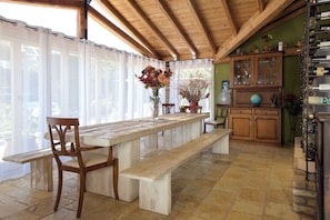 Un'area pranzo in legno con una panca, sedie, un tavolo e un mobile con ante in vetro.