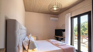A bedroom with a bed, a bedside table with a lamp, a TV, and a view of the outdoors through a sliding door. - Villa Irida - Holiday home with pool 400 meters from Agios Spyridon beach in Corfu (Acharavi)