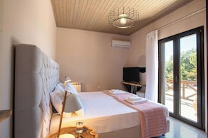 Camera da letto con un letto, un comodino con una lampada, una televisione e vista sull'esterno tramite una porta scorrevole.