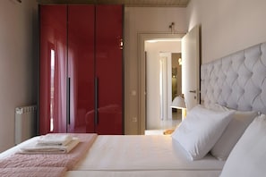 A hotel room with a bed, a red wardrobe, and a white headboard. - Villa Irida by PosarelliVillas (Acharavi)