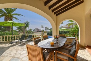 An outdoor patio with a round table, chairs, and a green umbrella.