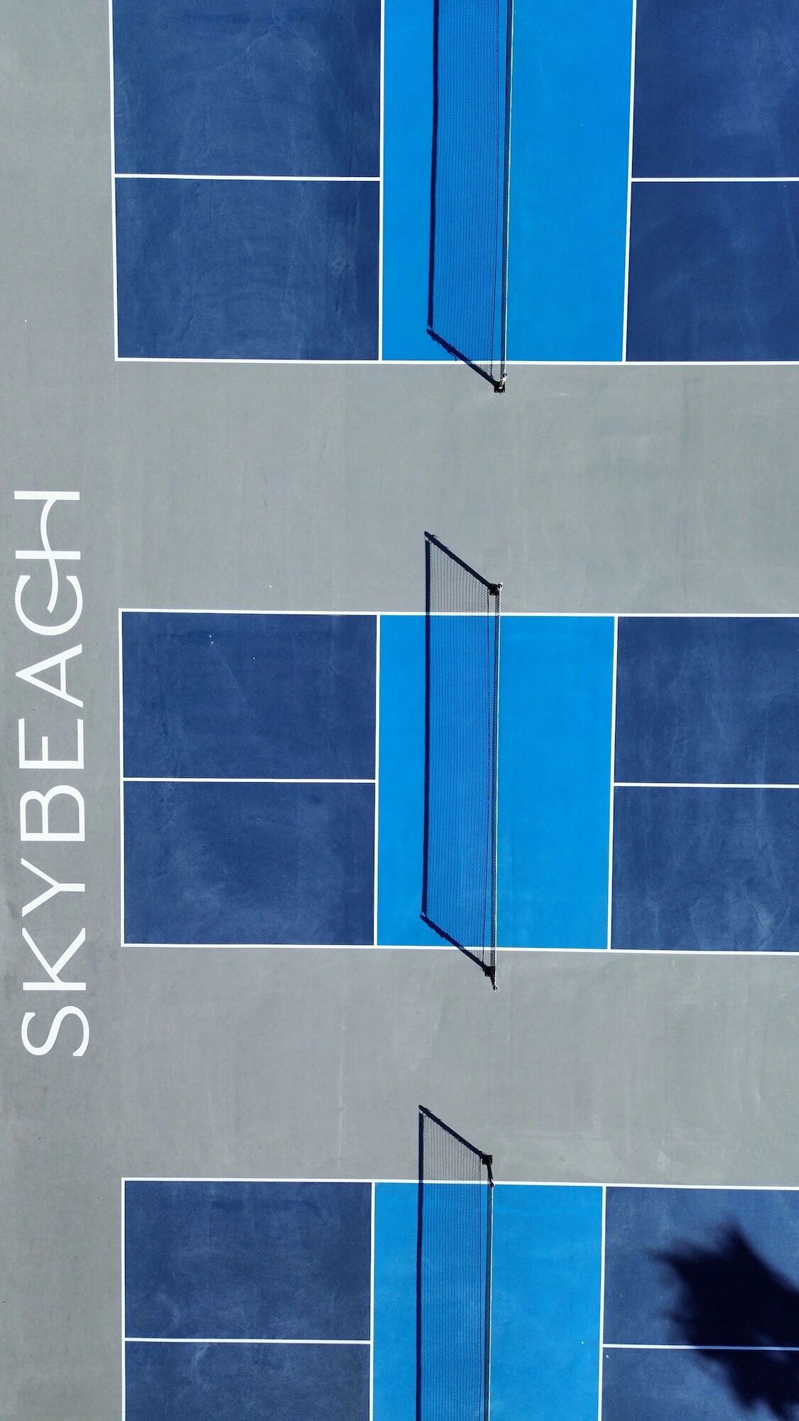 A tennis court with a net and the word "SKYBEACH" on the wall.