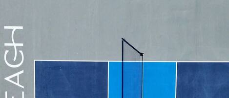 A tennis court with a net and the word "SKYBEACH" on the wall.