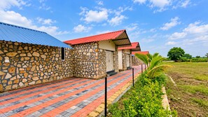 Une rangée de bâtiments aux murs de pierre, coiffés de toits rouges, et bordée d’une allée pavée.