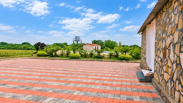 Un patio con un muro de piedra, un depósito de agua y un edificio con techo rojo.