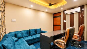A conference room with a blue sectional sofa, a black conference table, and a brown leather chair.