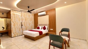 A modern bedroom with a bed, bedside chairs, a wardrobe, and an air conditioning unit. - Divydrashti Resorts (Waghoriya)