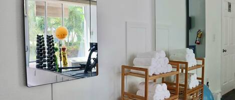 Un baño con un espejo grande, un perchero de madera y una ventana con vistas a equipo de ejercicio al aire libre.