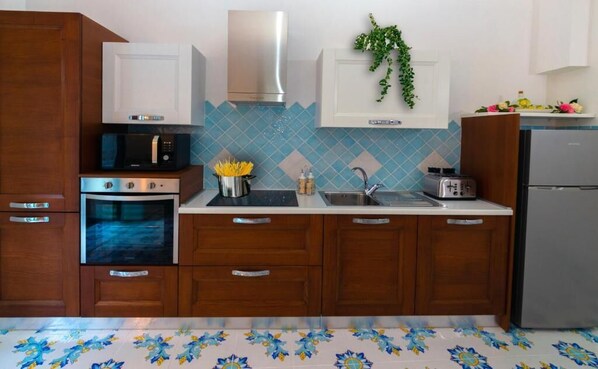 A kitchen with wooden cabinets, a microwave, an oven, a sink, and a refrigerator.