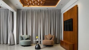 A modern living room with two sofas, a small side table with a vase, and a wooden entertainment unit with a TV. - GOLDEN CASTLE (Neyyattinkara)