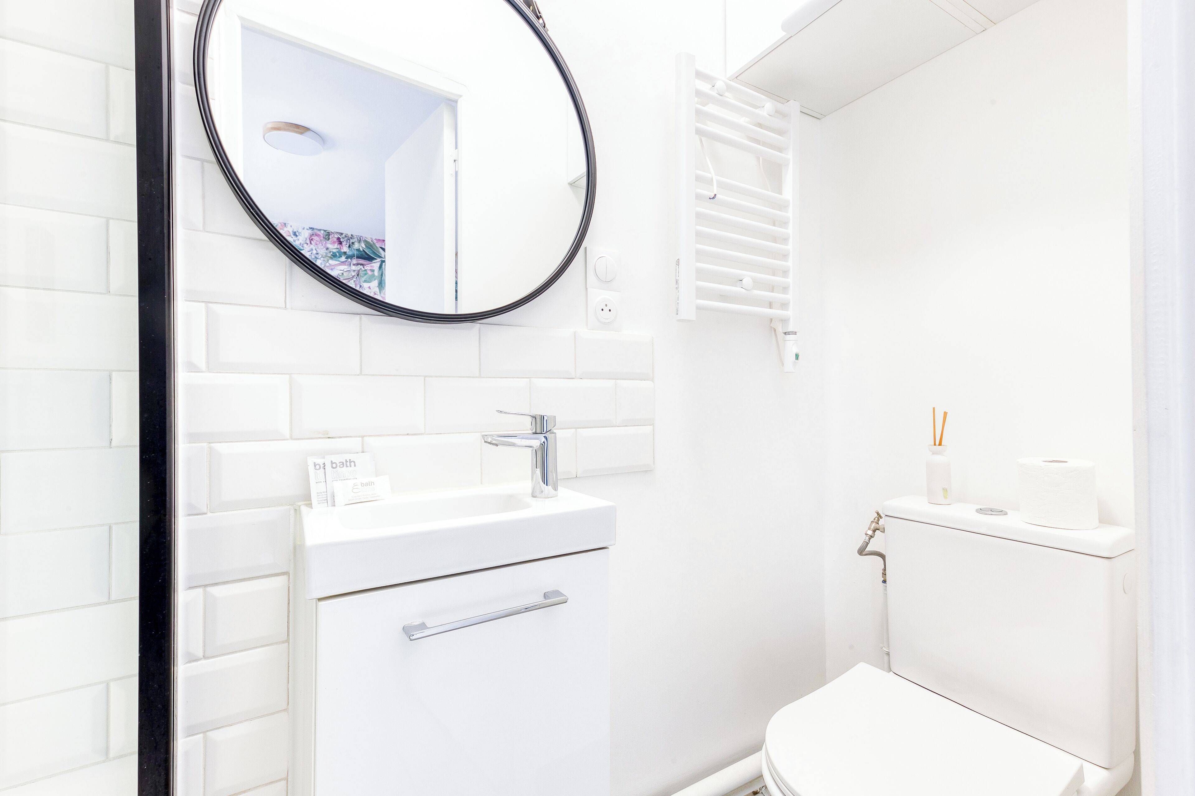 A modern bathroom with a white sink, mirror, and toilet.