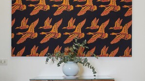 A wooden desk with a vase of green foliage and a patterned wall hanging above. - Charming and quiet two-room flat in Porta Romana (Milano)