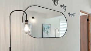 A wall-mounted mirror with a black frame and a single light fixture. - New 3-BR Apartment, A/C, Free Parking, Washer Dryer, Full Kitchen, WiFi (San Juan)