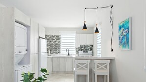 A modern kitchen with white cabinetry, a tiled backsplash, and a central island with bar stools. - New 3-BR Apartment, A/C, Free Parking, Washer Dryer, Full Kitchen, WiFi (San Juan)