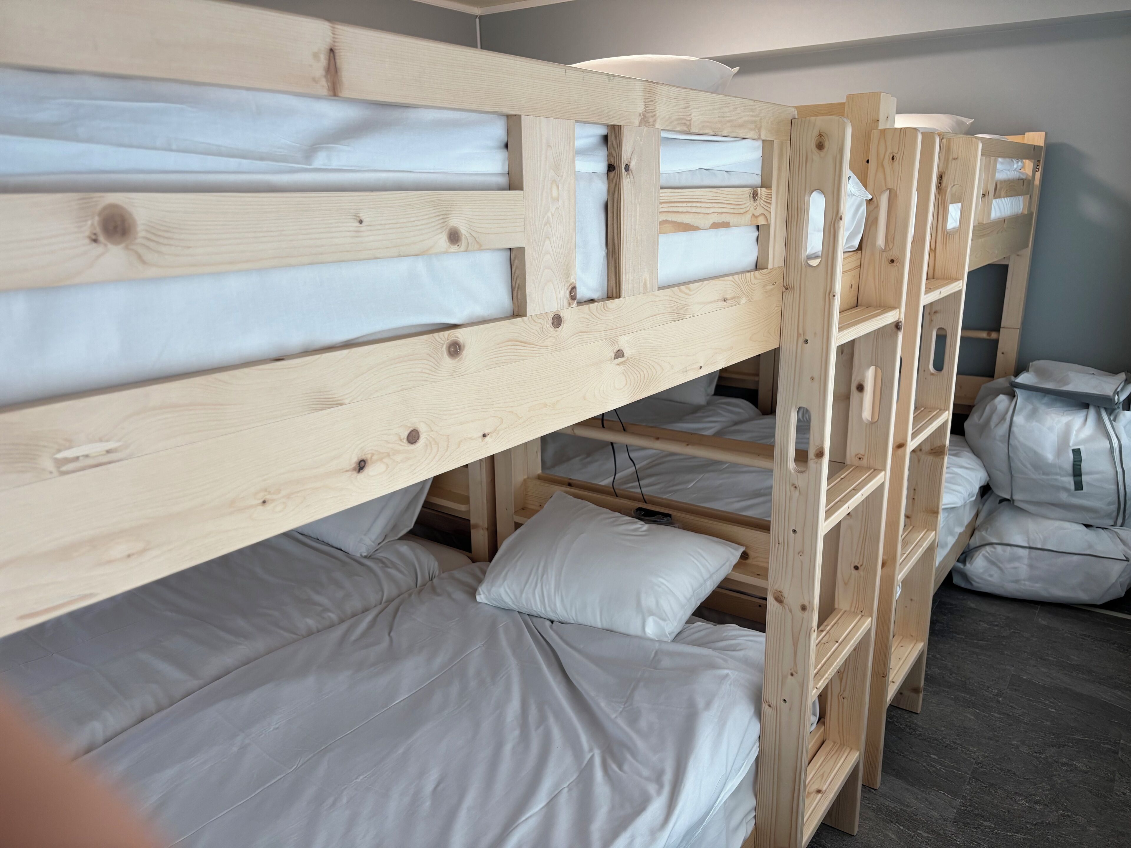 A bunk bed room with wooden frames and white bedding.