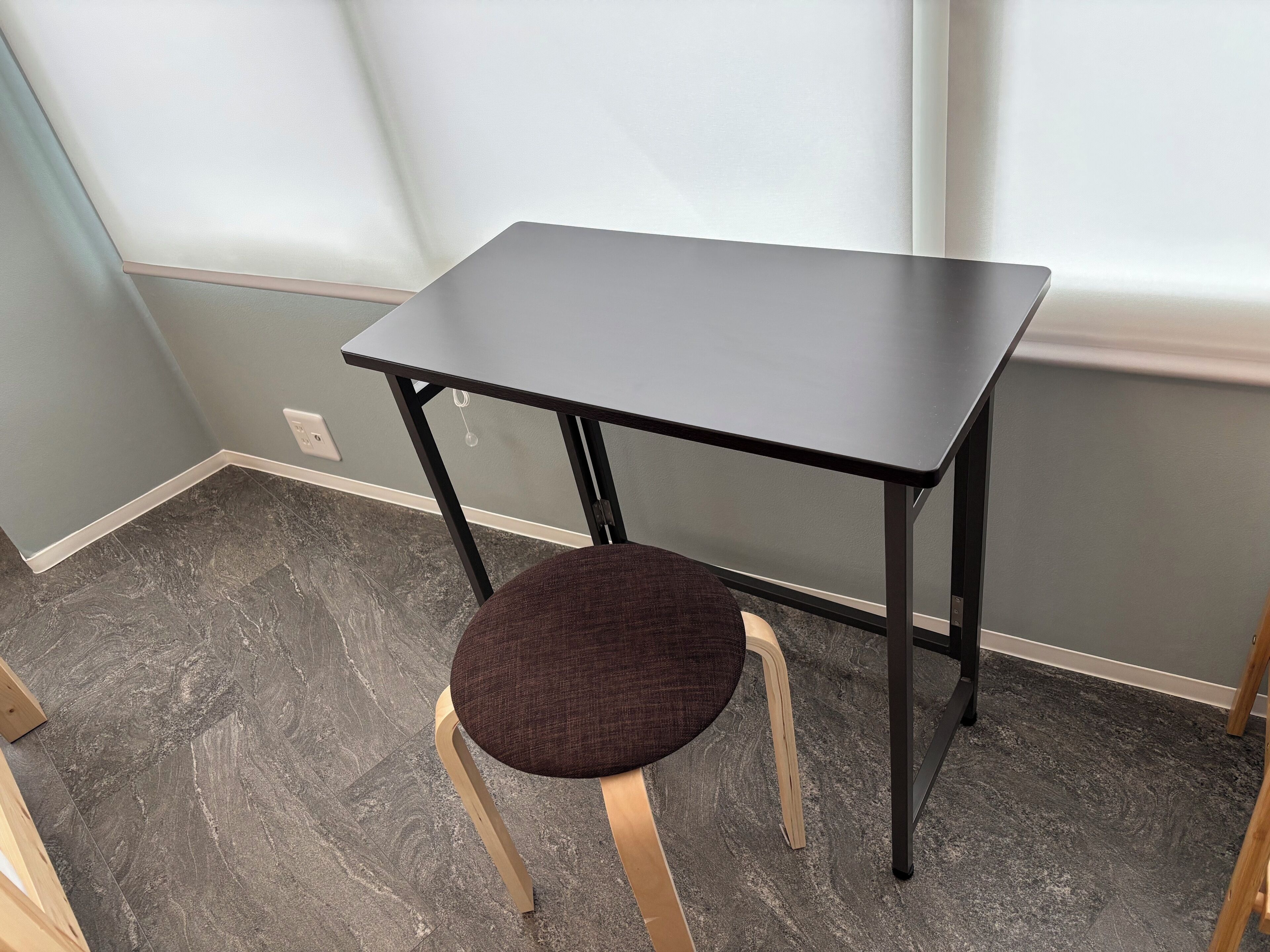 A small, dark-colored table with a single chair in front of it.